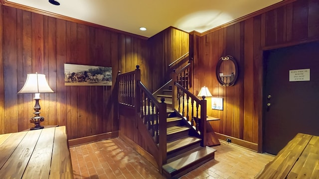 stairs with baseboards, brick floor, and wooden walls