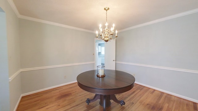 unfurnished dining area with a chandelier, ornamental molding, baseboards, and wood finished floors