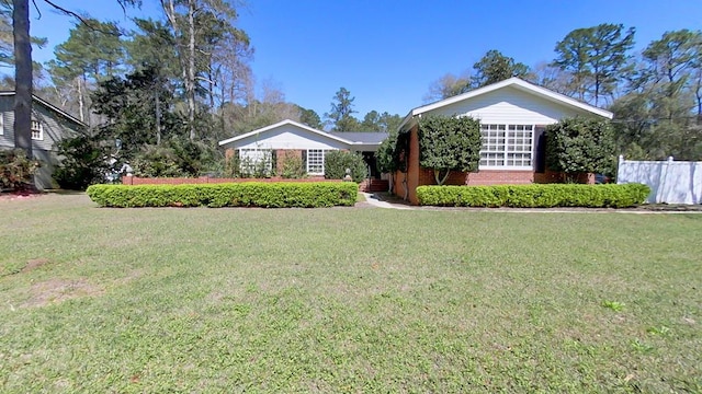 ranch-style home featuring a front lawn, fence, and brick siding