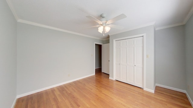 unfurnished bedroom with a closet, crown molding, light wood-type flooring, and baseboards