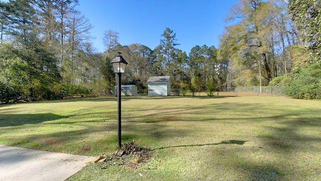 view of yard with an outbuilding, fence, and a shed