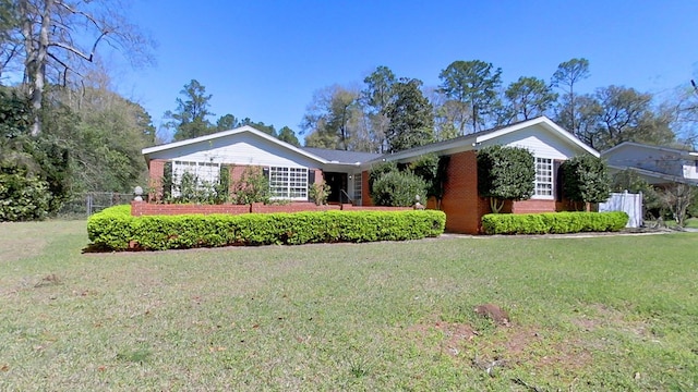 ranch-style house featuring brick siding, a front yard, and fence