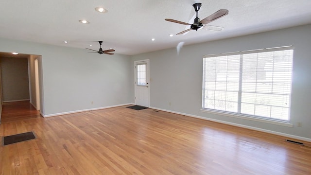 empty room featuring visible vents, light wood-style floors, baseboards, and ceiling fan