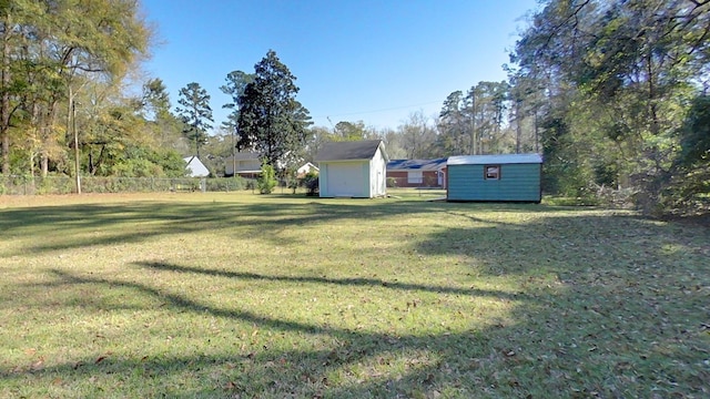 view of yard with an outbuilding, a storage unit, and fence