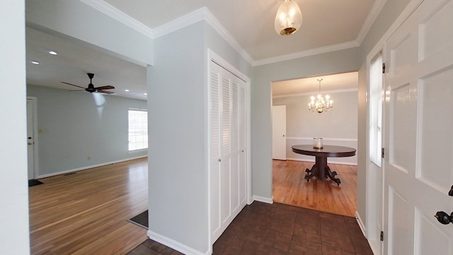 corridor featuring baseboards, dark wood-style flooring, a chandelier, and ornamental molding