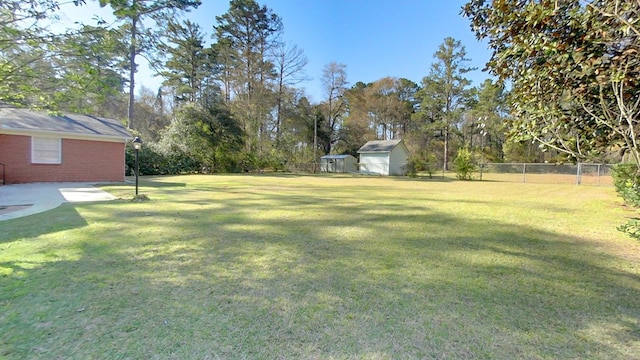 view of yard with a shed, an outdoor structure, and fence