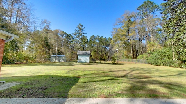 view of yard featuring an outbuilding, a storage shed, and fence