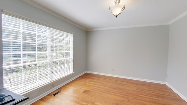 unfurnished room featuring light wood finished floors, visible vents, crown molding, and baseboards