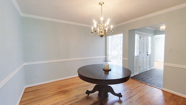 dining room featuring ornamental molding, baseboards, an inviting chandelier, and wood finished floors