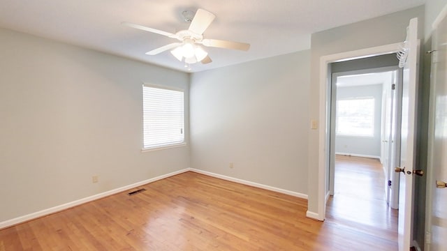 unfurnished room with a ceiling fan, baseboards, visible vents, and light wood finished floors