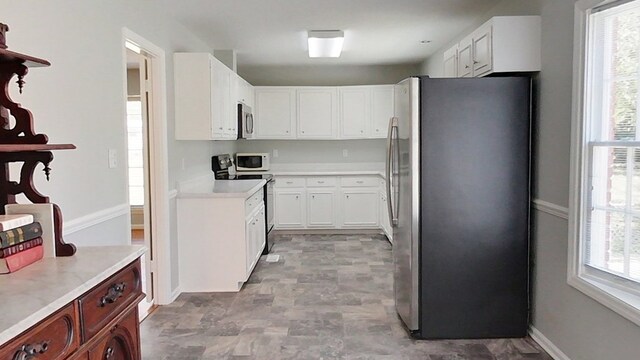 kitchen featuring appliances with stainless steel finishes, white cabinets, and light countertops