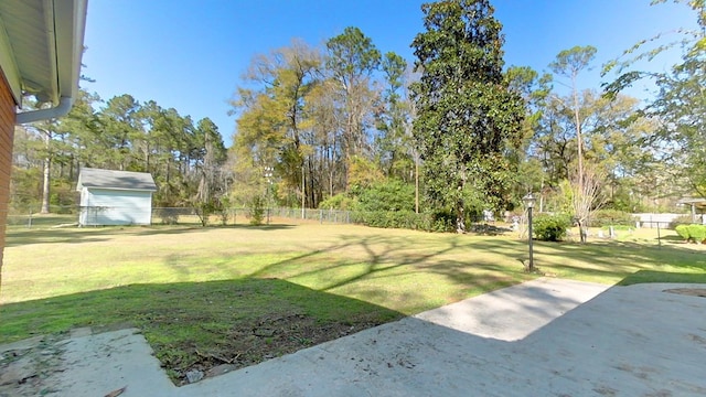 view of yard featuring an outbuilding, a patio area, a storage unit, and fence