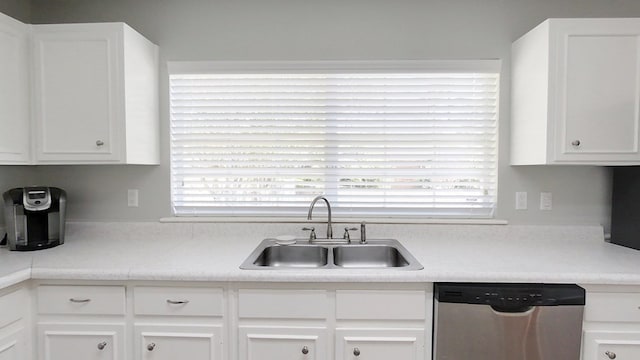 kitchen with stainless steel dishwasher, light countertops, white cabinets, and a sink