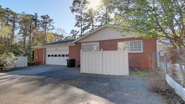 view of side of property with crawl space, driveway, brick siding, and an attached garage