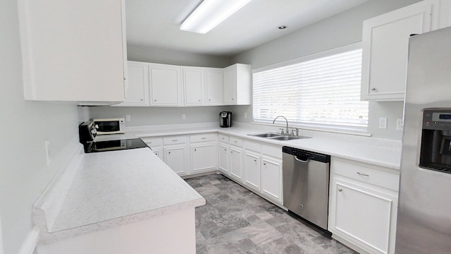 kitchen featuring white cabinetry, stainless steel appliances, light countertops, and a sink