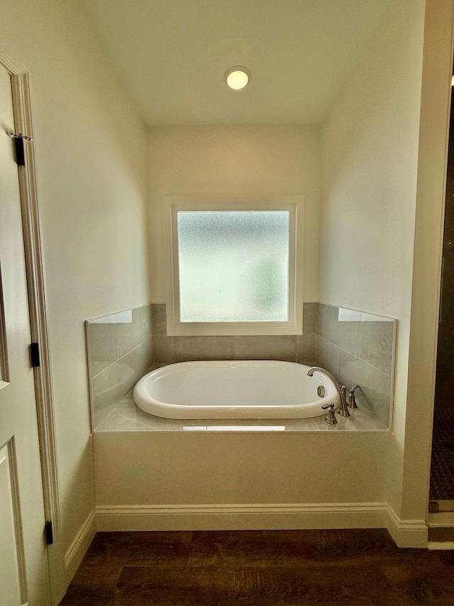 bathroom featuring hardwood / wood-style floors and tiled tub