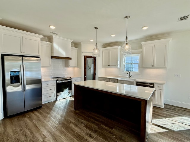 kitchen with wall chimney exhaust hood, sink, a kitchen island, stainless steel appliances, and white cabinets