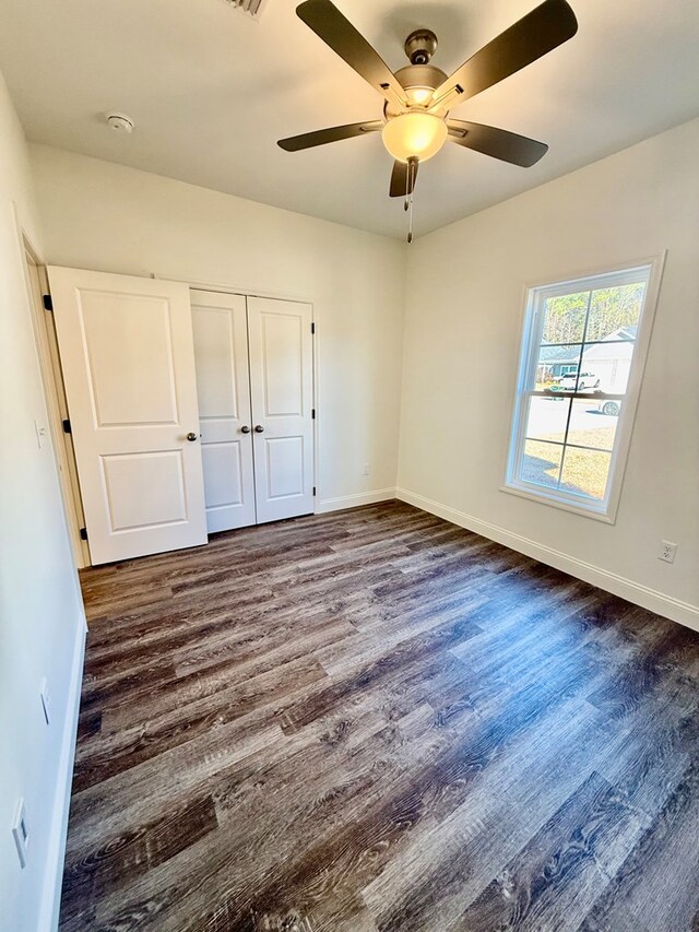 unfurnished bedroom with ceiling fan, dark hardwood / wood-style flooring, and a closet