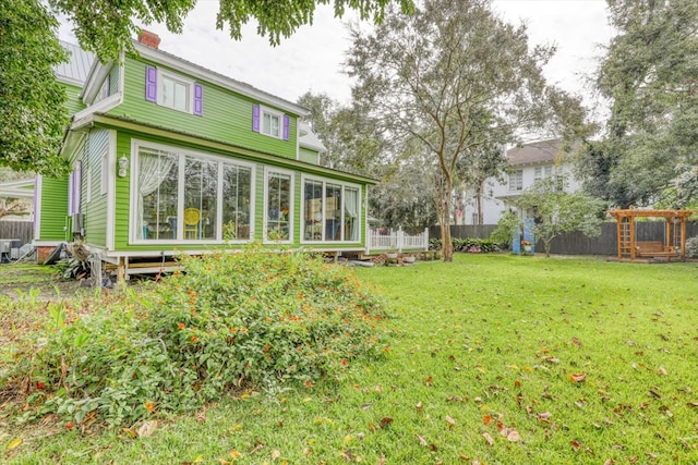 back of house with a sunroom and a lawn