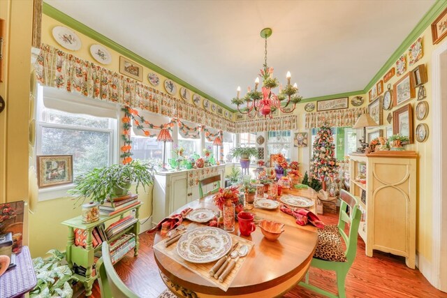 dining space with ornamental molding, a notable chandelier, and light hardwood / wood-style flooring