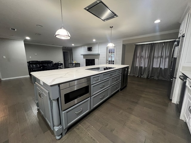 kitchen featuring appliances with stainless steel finishes, light stone countertops, hanging light fixtures, and a kitchen island