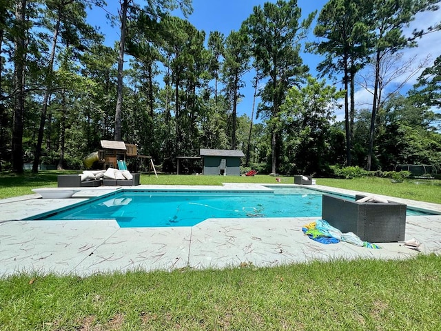 view of pool featuring a storage unit, a playground, a lawn, and a diving board