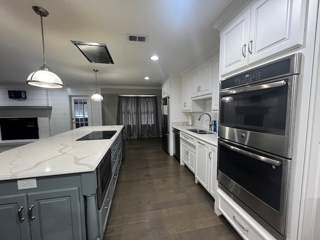 kitchen with sink, decorative light fixtures, black appliances, and white cabinets