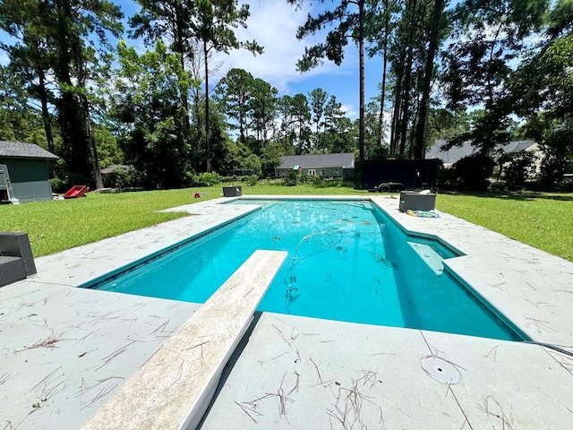 view of swimming pool featuring a diving board and a lawn