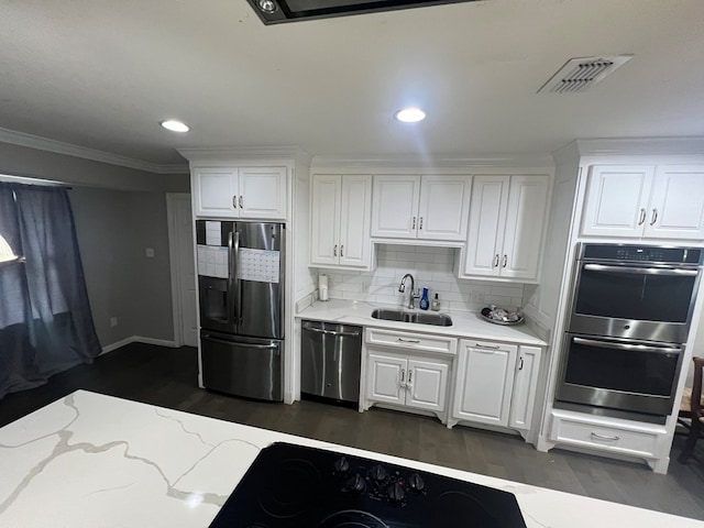 kitchen with appliances with stainless steel finishes, sink, white cabinets, and backsplash