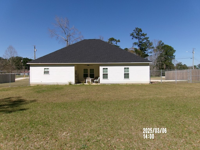 back of house with fence, a ceiling fan, and a yard