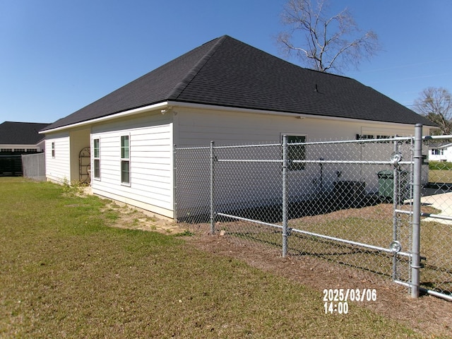 view of home's exterior with a shingled roof, fence, and a yard