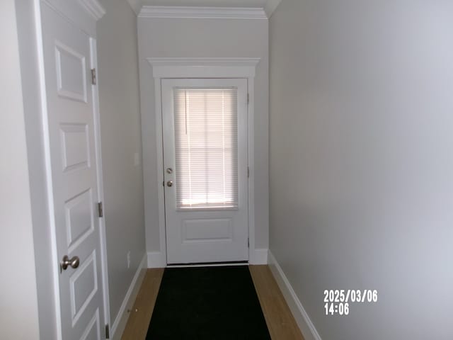 doorway to outside with baseboards, ornamental molding, and wood finished floors