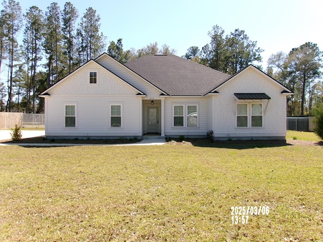 modern farmhouse style home featuring a front yard, roof with shingles, and fence