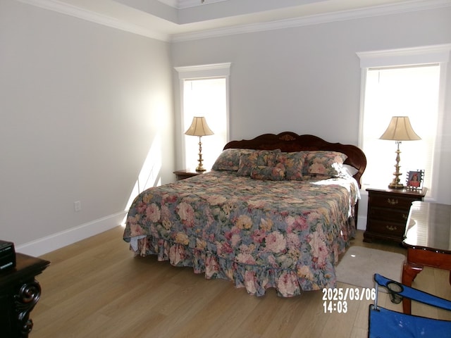 bedroom with crown molding, baseboards, and wood finished floors