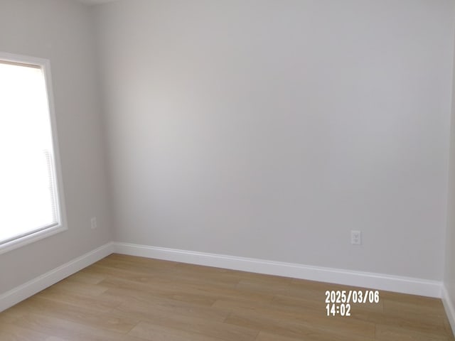 spare room featuring light wood finished floors and baseboards