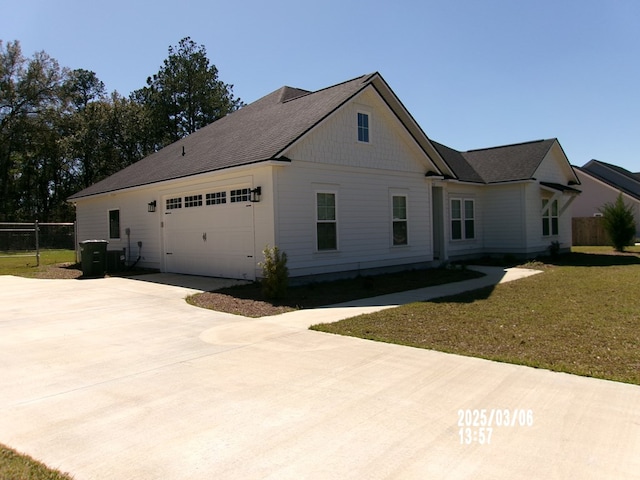 view of side of home featuring driveway, a yard, an attached garage, and fence