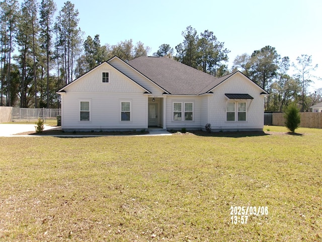 modern inspired farmhouse featuring roof with shingles, a front yard, and fence