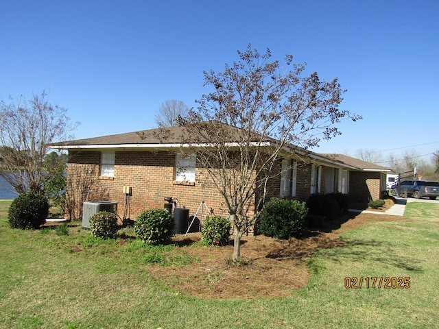 view of side of home with cooling unit and a lawn