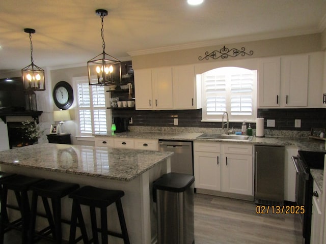 kitchen with decorative light fixtures, dishwasher, sink, white cabinets, and crown molding