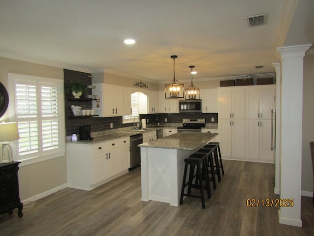 kitchen with stainless steel appliances, crown molding, a center island, and pendant lighting