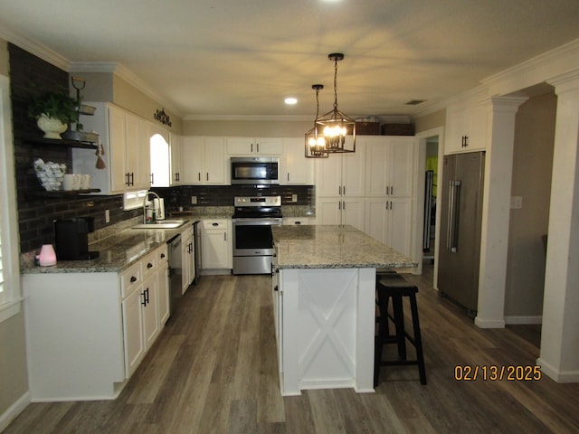 kitchen featuring sink, appliances with stainless steel finishes, hanging light fixtures, a center island, and white cabinets