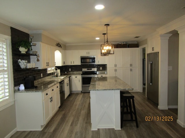 kitchen with white cabinetry, decorative light fixtures, stainless steel appliances, and a center island