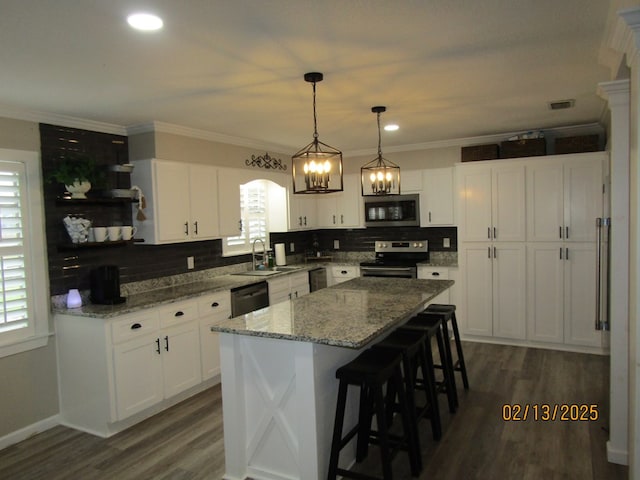 kitchen with sink, white cabinetry, light stone counters, a center island, and appliances with stainless steel finishes