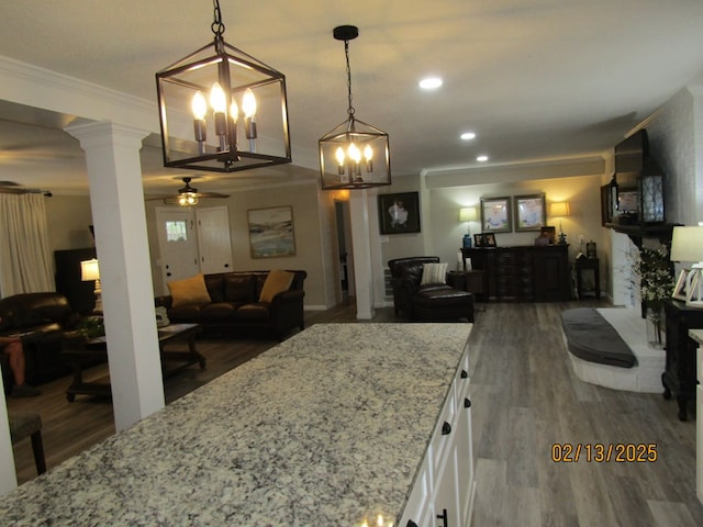 kitchen featuring white cabinetry, light stone counters, pendant lighting, and ornamental molding