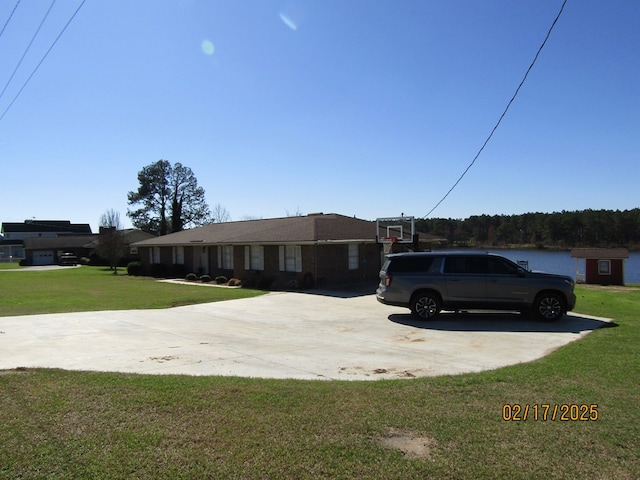 ranch-style home featuring a front lawn and basketball hoop