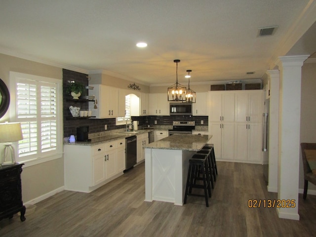 kitchen with white cabinetry, stainless steel appliances, dark stone counters, and a kitchen island