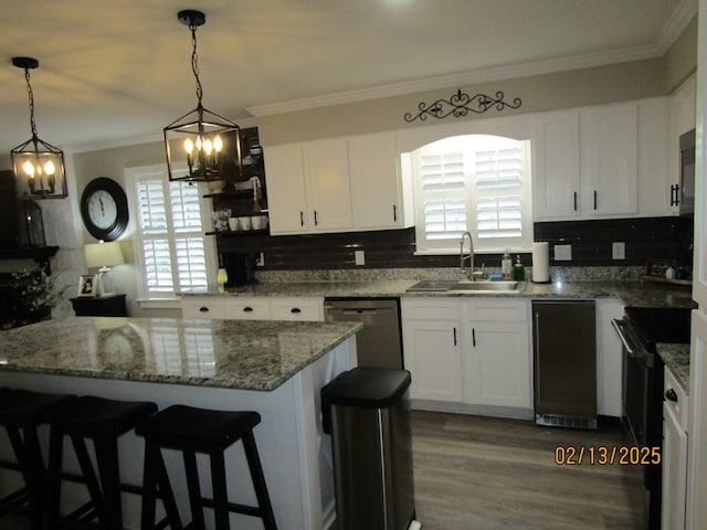 kitchen featuring white cabinetry, stainless steel dishwasher, decorative light fixtures, and sink