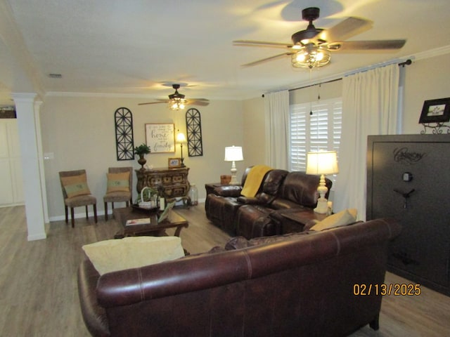 living room featuring decorative columns, wood-type flooring, ornamental molding, and ceiling fan