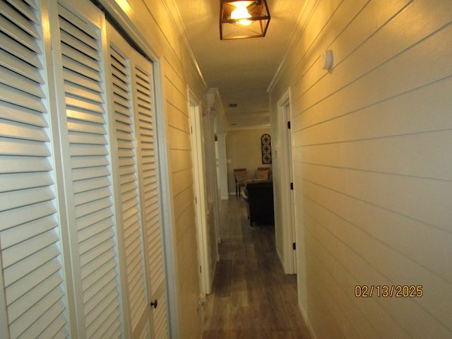 hallway with dark hardwood / wood-style flooring, wooden walls, and ornamental molding