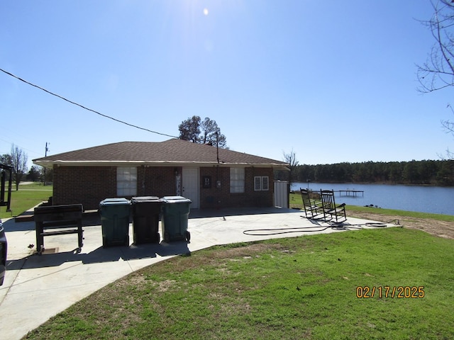 rear view of property featuring a water view, a patio area, and a lawn